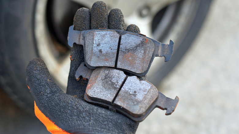 A Mechanic Holding Worn Brake Pads