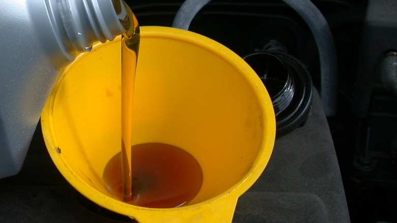 Motor oil being poured into a yellow funnel