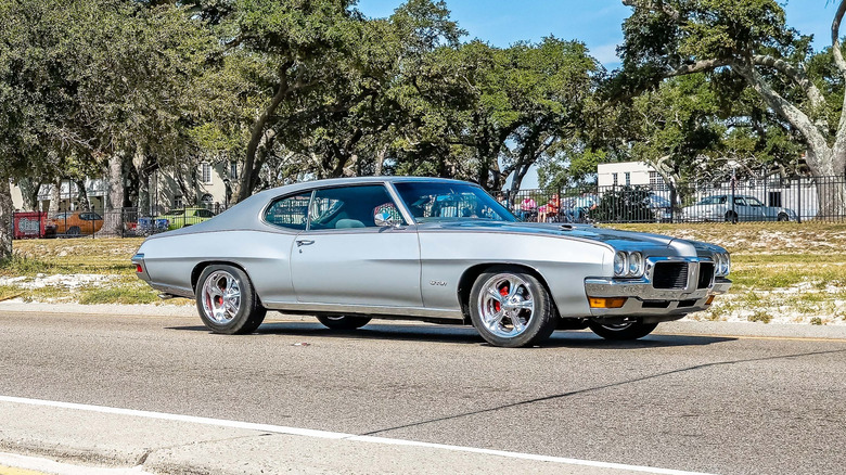 Silver 1971 Pontiac GT-37 with custom wheels seen from the right in a parking lot
