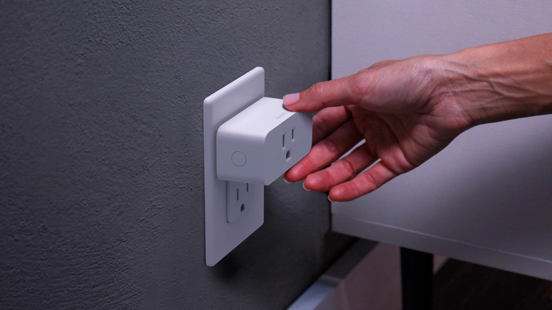 Man inserts Philips Hue Smart Plug into an outlet