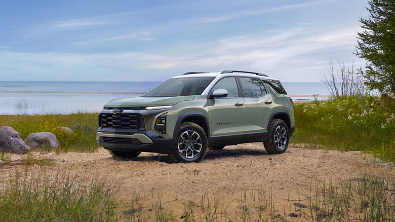 Green 2025 Chevrolet Equinox seen from left front in front of a lake