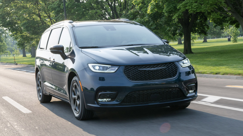 Black 2025 Chrysler Pacifica Plug-in Hybrid seen from front right on a tree-shaded road