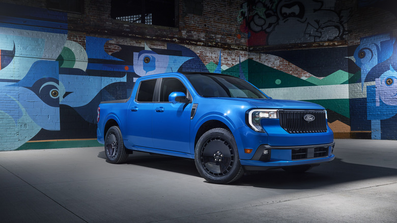 Blue 2025 Ford Maverick Lobo pickup truck seen from right front against a post-industrial abstract painted background