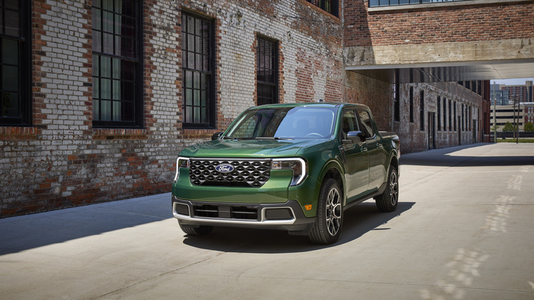 Green 2025 Ford Maverick pickup seen from front left near a factory