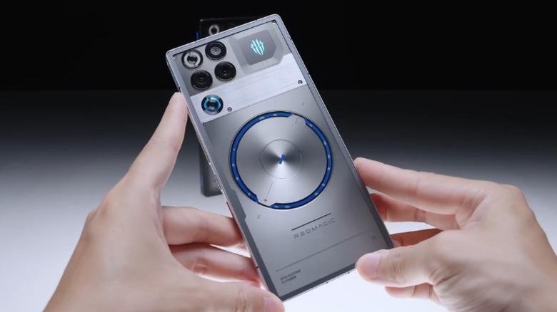 Hands holding silver RedMagic 11S Pro phone against a gradient backdrop