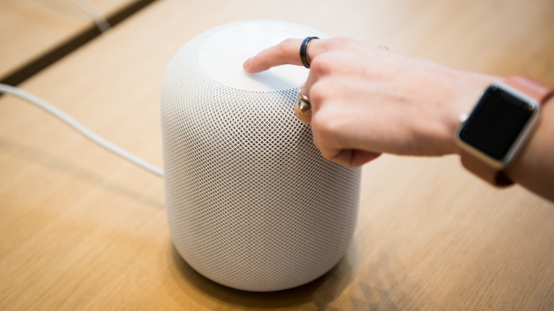 Person wearing an Apple Watch tapping a HomePod