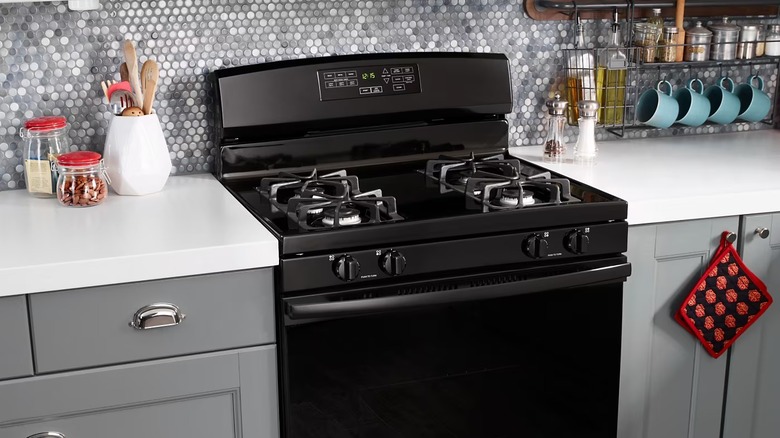 A black Amana cooktop range installed in a white and gray kitchen