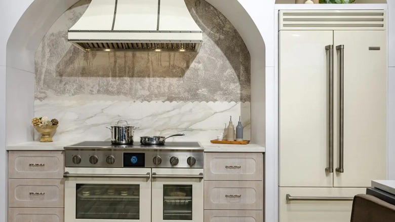 A BlueStar dual-fuel range in an off-white finish with a matching custom hood, paired with a tall French door refrigerator.