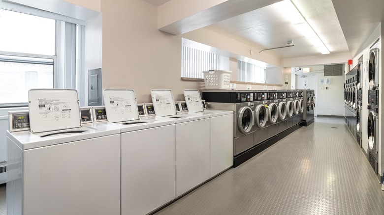 A laundromat running a row of white Speed Queen top-load washers down one side and a bank of front-load dryers down the other.