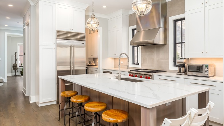 A bright kitchen showing a stainless steel Sub-Zero built-in refrigerator and a red-knobbed professional range.