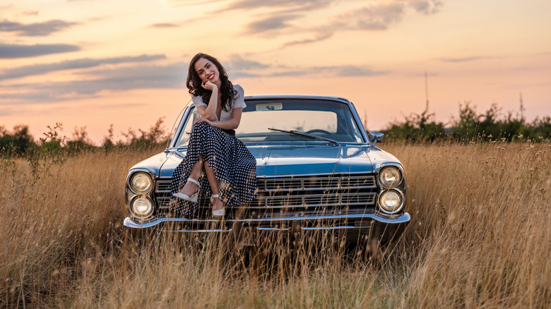 Relaxing on a vintage coupe's hood during the sunset