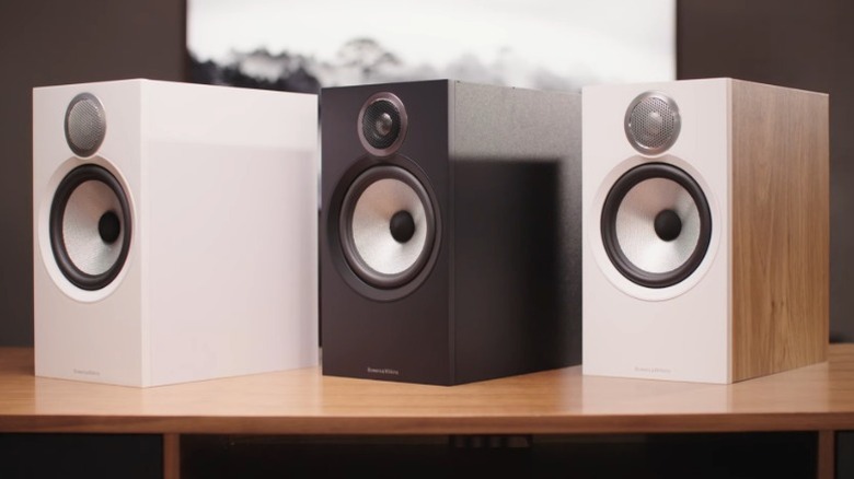 White, black, and wood-grain Bowers & Wilkins 606 speakers on a wood table.