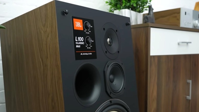 Close-up of JBL L100 Classic MkII speaker next to a wood cabinet.