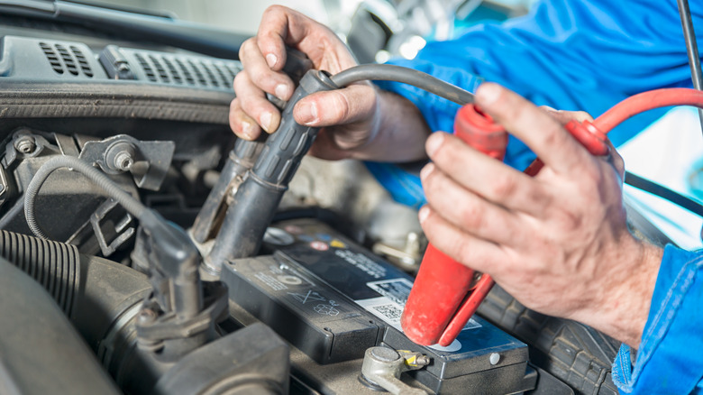 A man connects jumper cables to a car battery