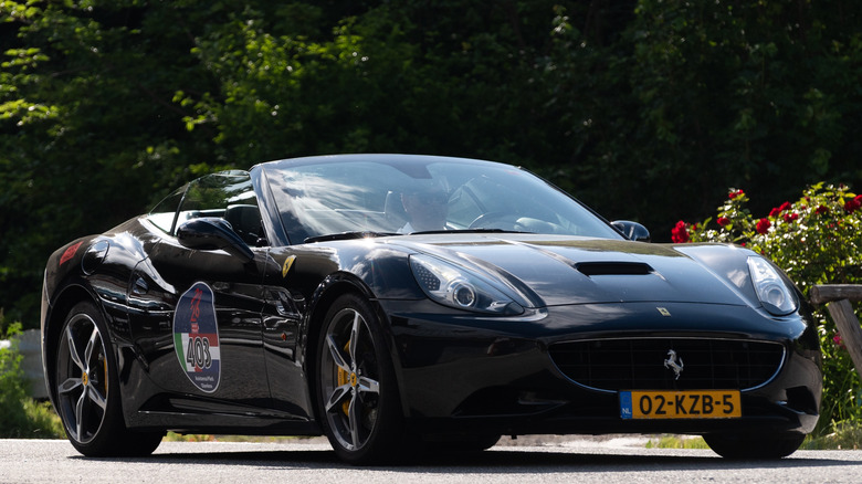 Black Ferrari Cabriolet convertible driving.