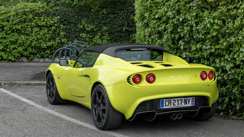 Green Lotus Elise S parked by a hedge.