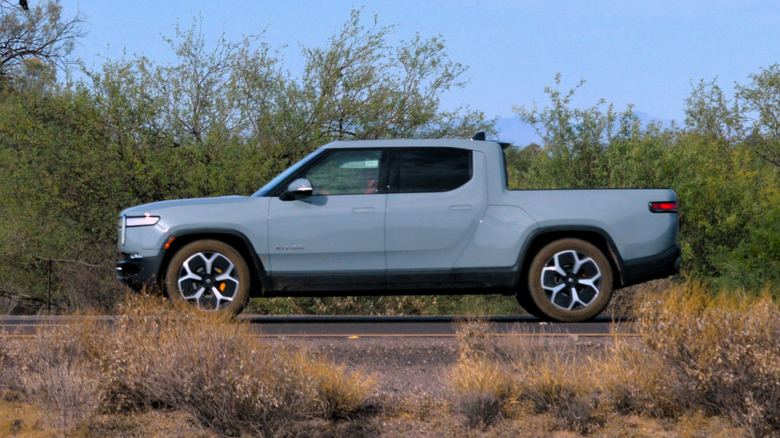 Cobalt Rivian R1T parked by brushes.