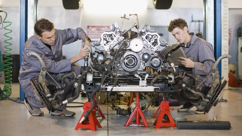 Two men fixing an engine