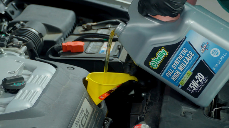 pouring oil into an engine via funnel