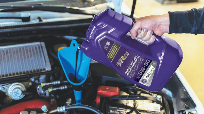 pouring oil into an engine via funnel