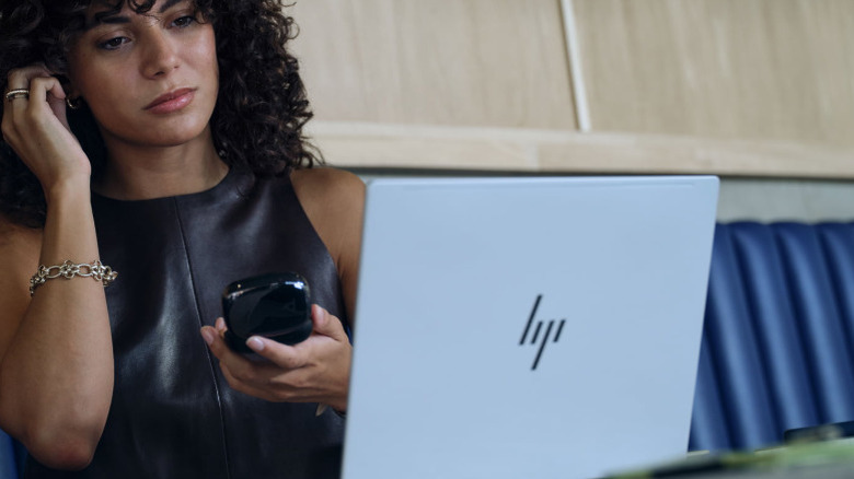 Woman wearing earbuds while looking at HP Omnibook Ultra