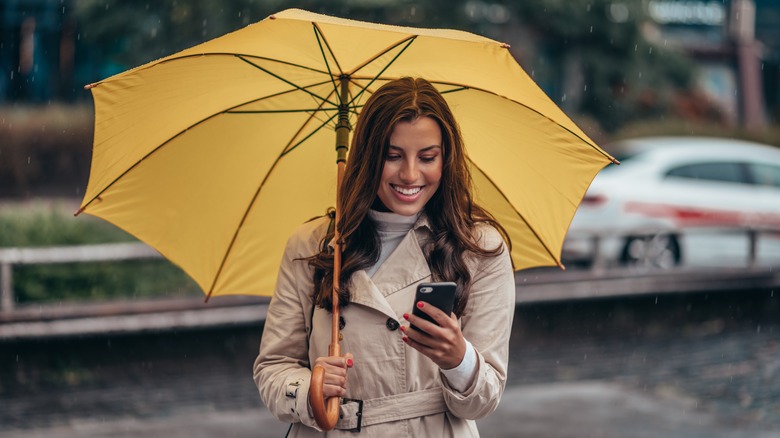 Woman in rain checking her smartphone