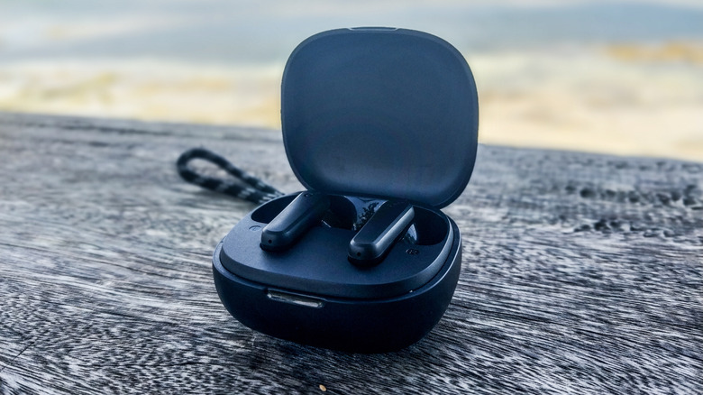 A pair of wireless earbuds resting in an open case, placed on a gray surface