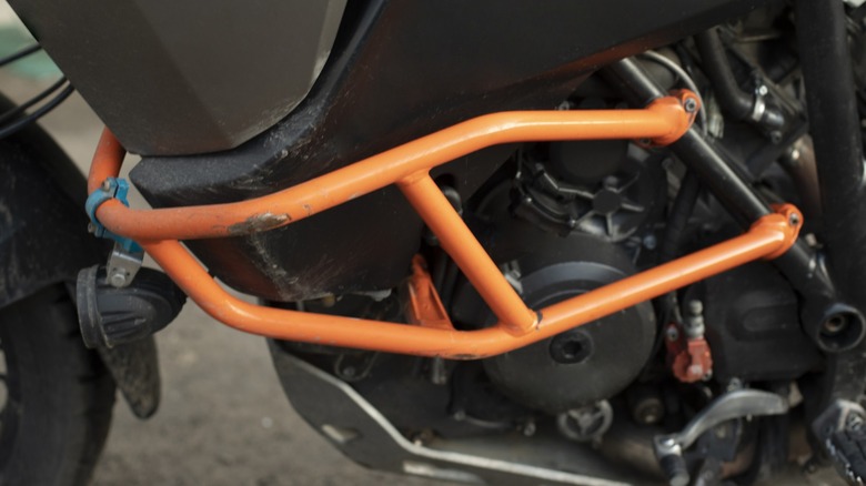 a scratched orange crash guard install over the engine of a motorcycle
