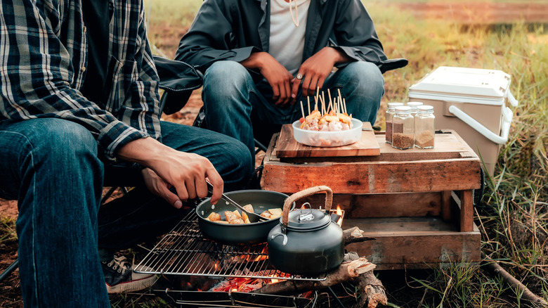 two men using a simple camp cooking setup