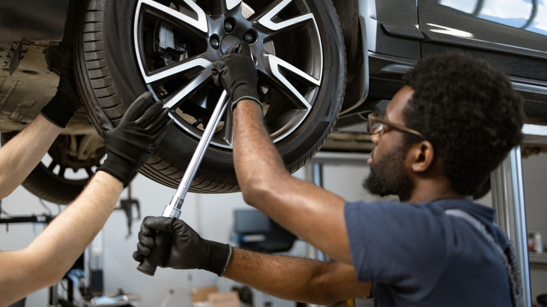Mechanic fitting a wheel with a set of helping hands