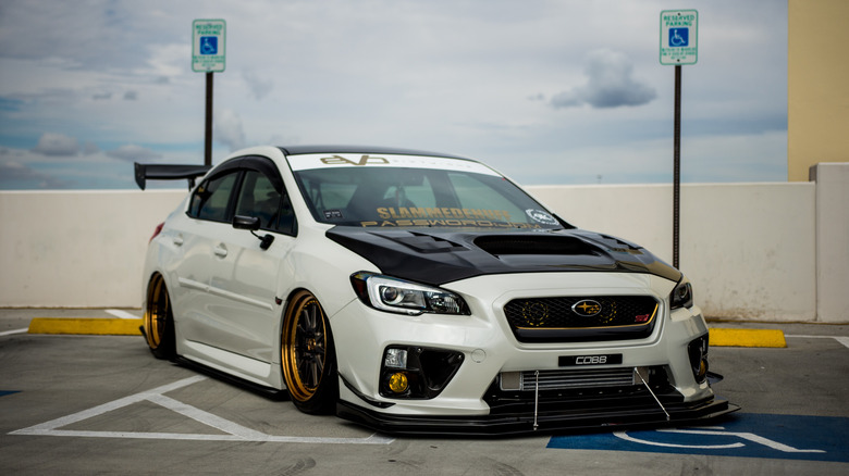 A modded Subaru parked across a reserved spot