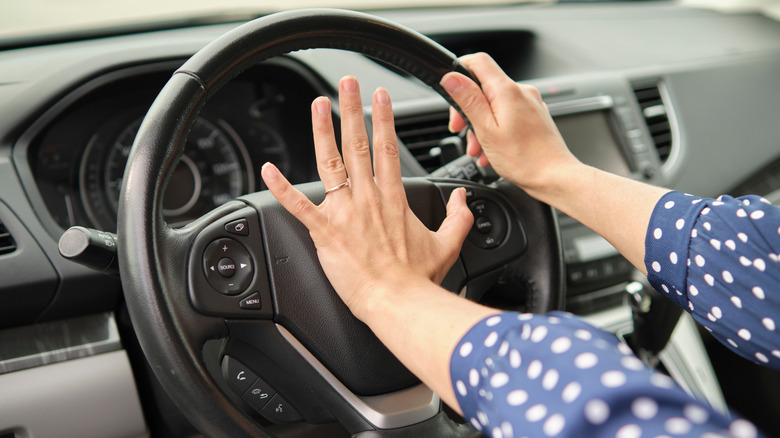 A person pressing a car horn