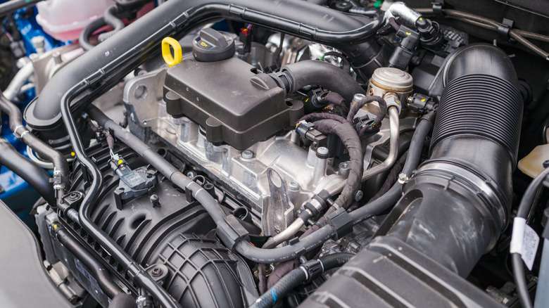 A car hood up with the focus on an engine block