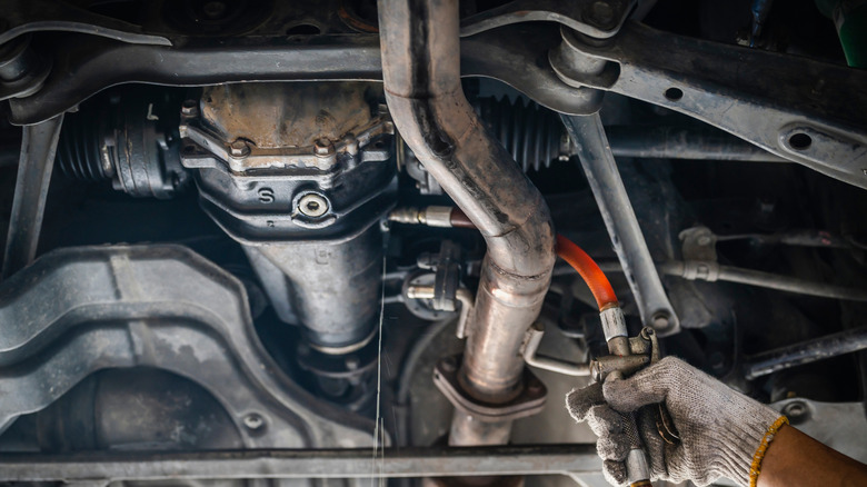 Mechanic removing differential fluid from under a car