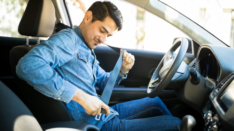 Man strapping down a seat belt in his car.