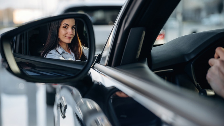 Woman looks in the side view mirror while driving