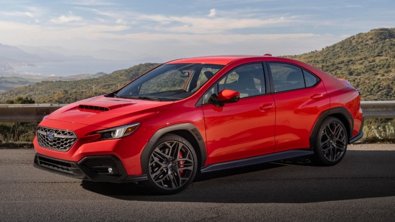 Red Subaru WRX parked on a mountain road with mountain valley in the background