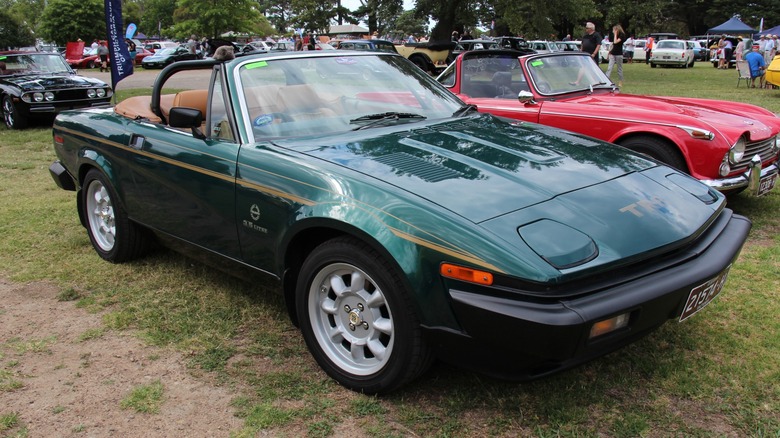 Green Triumph TR8 convertible parked on grass at a car show