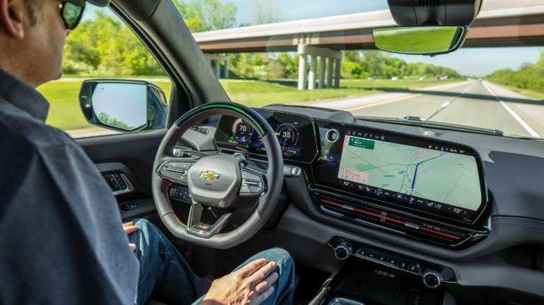 Person in Chevrolet Silverado EV cockpit with both screens visible