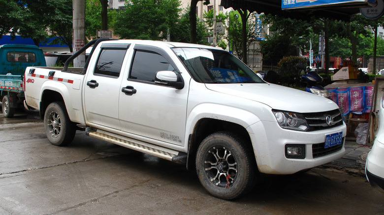 A white JMCGL T7 pickup truck resembling a VW Amarok parked at the side of a street