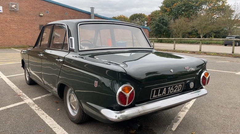 a white and green 1963 Ford Cortina GT, parked near a glass building