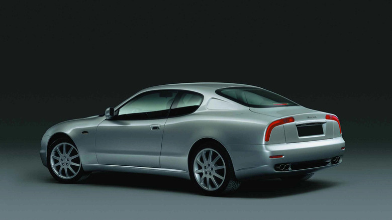Rear three-quarter view of a silver Maserati 3200GT, a luxury Italian grand tourer coupe, shown in a studio setting with dark background.