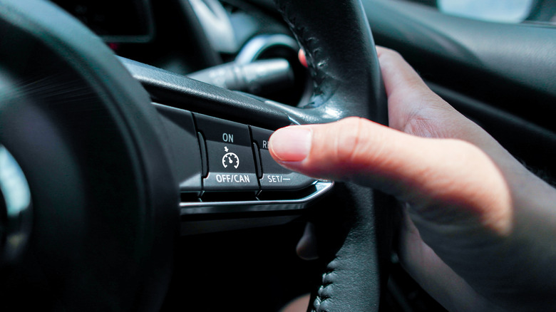 Driver with thumb over cruise control button