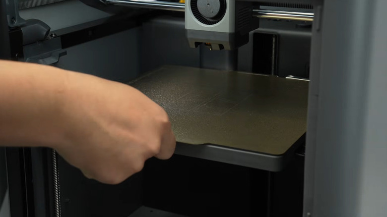 A person leveling the bed on their Bambu printer.