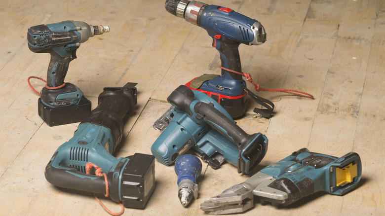 Multiple cordless power tools on a workbench or floor