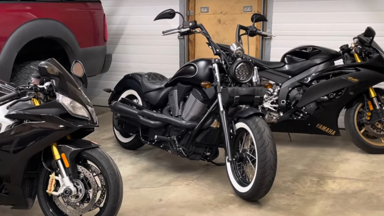 A Victory cruiser alongside two sport bikes from the brand parked outside a garage.
