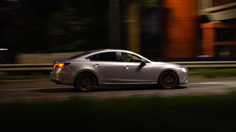 A car driving down a street at night.