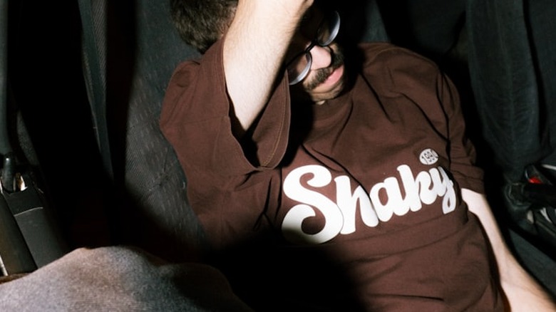 A man sitting inside of a car holding onto a steering wheel.