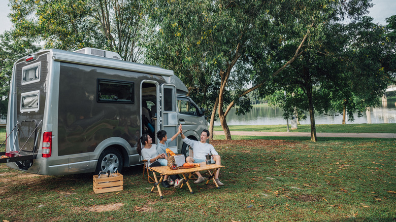 A family camped by a lake eating a meal.