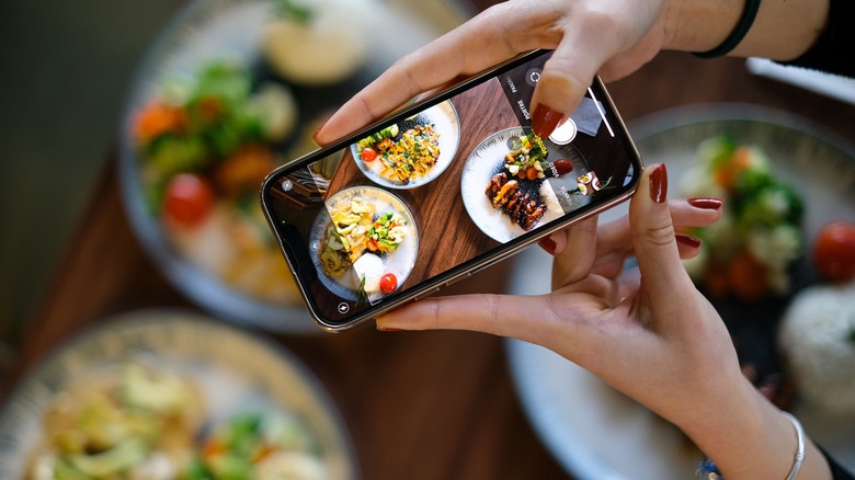 A woman shooting a photo of her food with a smartphone.